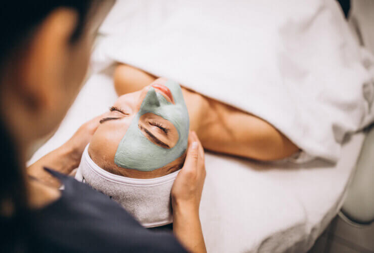A cosmetologist applying a mask to a client's face at a beauty salon, representing the growth and demand in the dermatology segment.