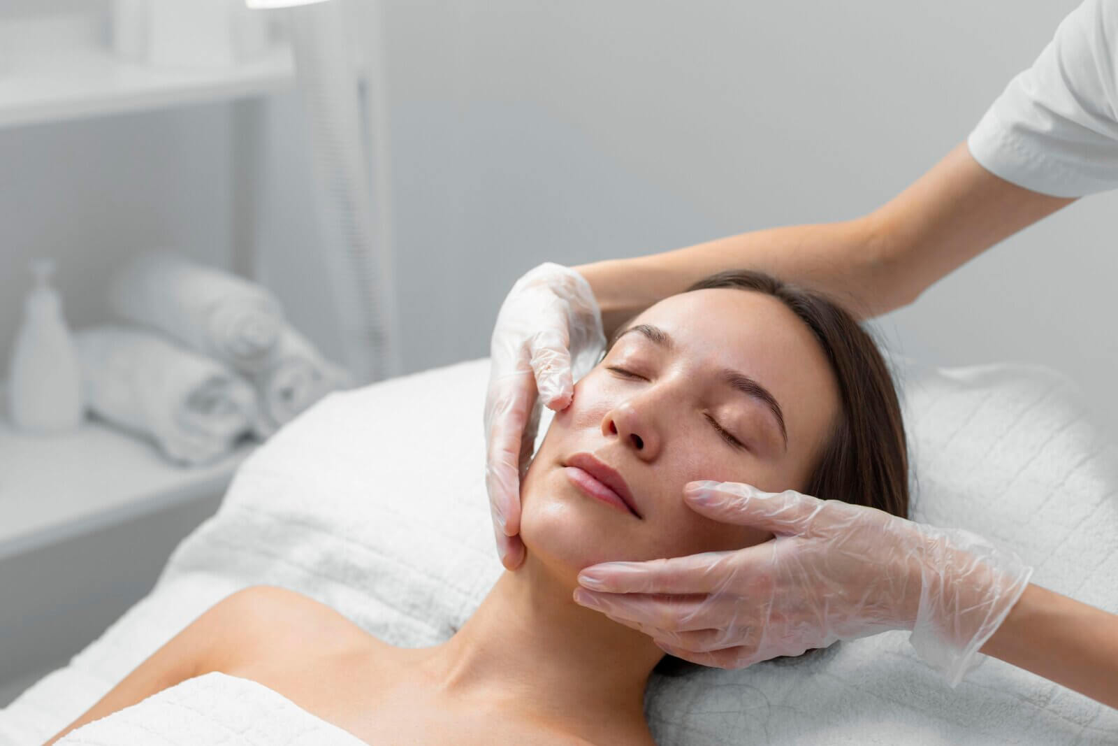 Young woman lying on a beautician's table receiving aesthetic treatments.