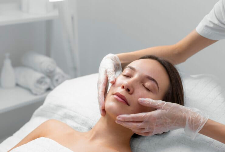 Young woman lying on a beautician's table receiving aesthetic treatments.