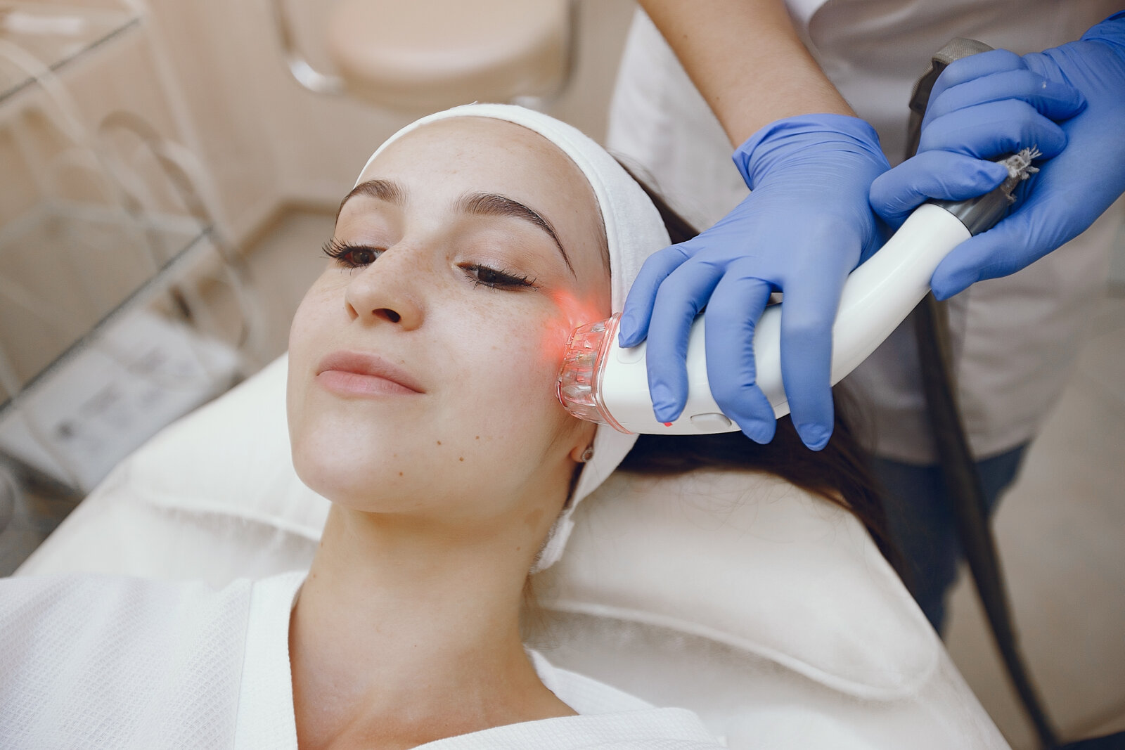 Professional using an aesthetic medical device on a woman at a cosmetology studio